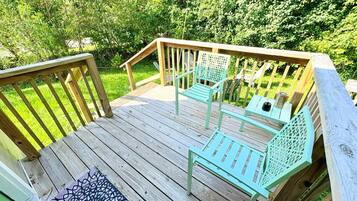 A wooden deck with a patterned mat, two chairs, and a small table.