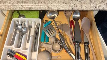 Eine Schublade mit Küchenutensilien, darunter Löffel, Gabeln, Messer und ein Multitool.