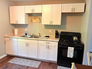 A kitchen with white cabinets, a black stove, a sink, and a countertop. - Muddy Boots HideoutI Cozy 2BR I 15m to RRG I Wi-Fi (Stanton)