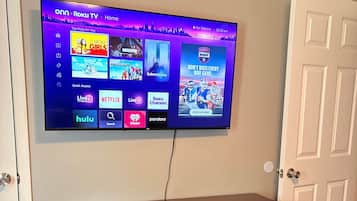 A flat-screen TV mounted on a wall with a dark wooden cabinet below it.