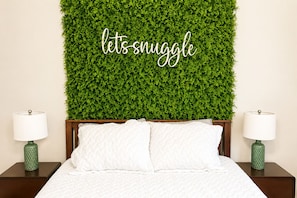 A bed with white bedding, two nightstands with lamps, and a green wall with a 'lets snuggle' sign. - Muddy Boots HideoutI Cozy 2BR I 15m to RRG I Wi-Fi (Stanton)