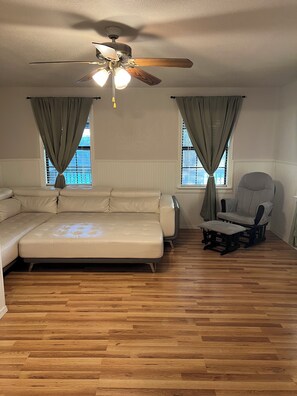 A room with a ceiling fan, a sofa, a chair, and a window with curtains. - Waterfront Retreat - Pier + Fishing + Fire Pit (Rio Hondo)