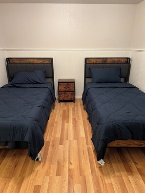 A room with two beds, a small wooden nightstand, and a wooden floor. - Waterfront Retreat - Pier + Fishing + Fire Pit (Rio Hondo)