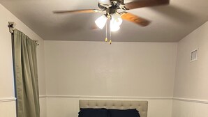 Ein Schlafzimmer mit einem Bett, einem Deckenventilator und einem Nachttisch.