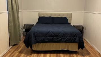 A bedroom with a bed, a ceiling fan, and a nightstand.