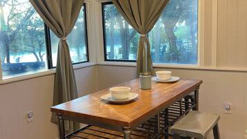 A dining area with a wooden table, two stools, and a ceiling fan.