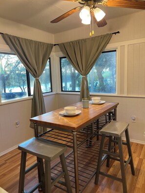 A dining area with a wooden table, two stools, and a ceiling fan. - Waterfront Retreat - Pier + Fishing + Fire Pit (Rio Hondo)