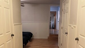 A hallway with wooden flooring, white walls, and doors on both sides.