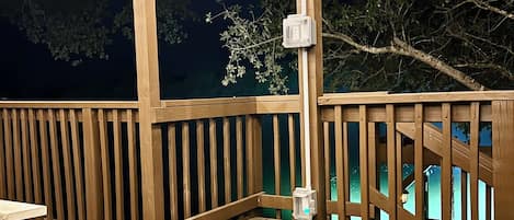 Een houten terras met twee ventilatoren, een leuning en uitzicht op de nachthemel.