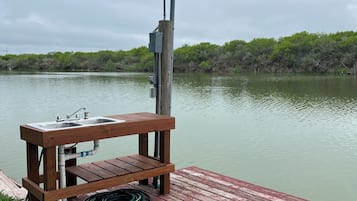 Un muelle de madera con un banco, un lavamanos y una lámpara con energía solar.
