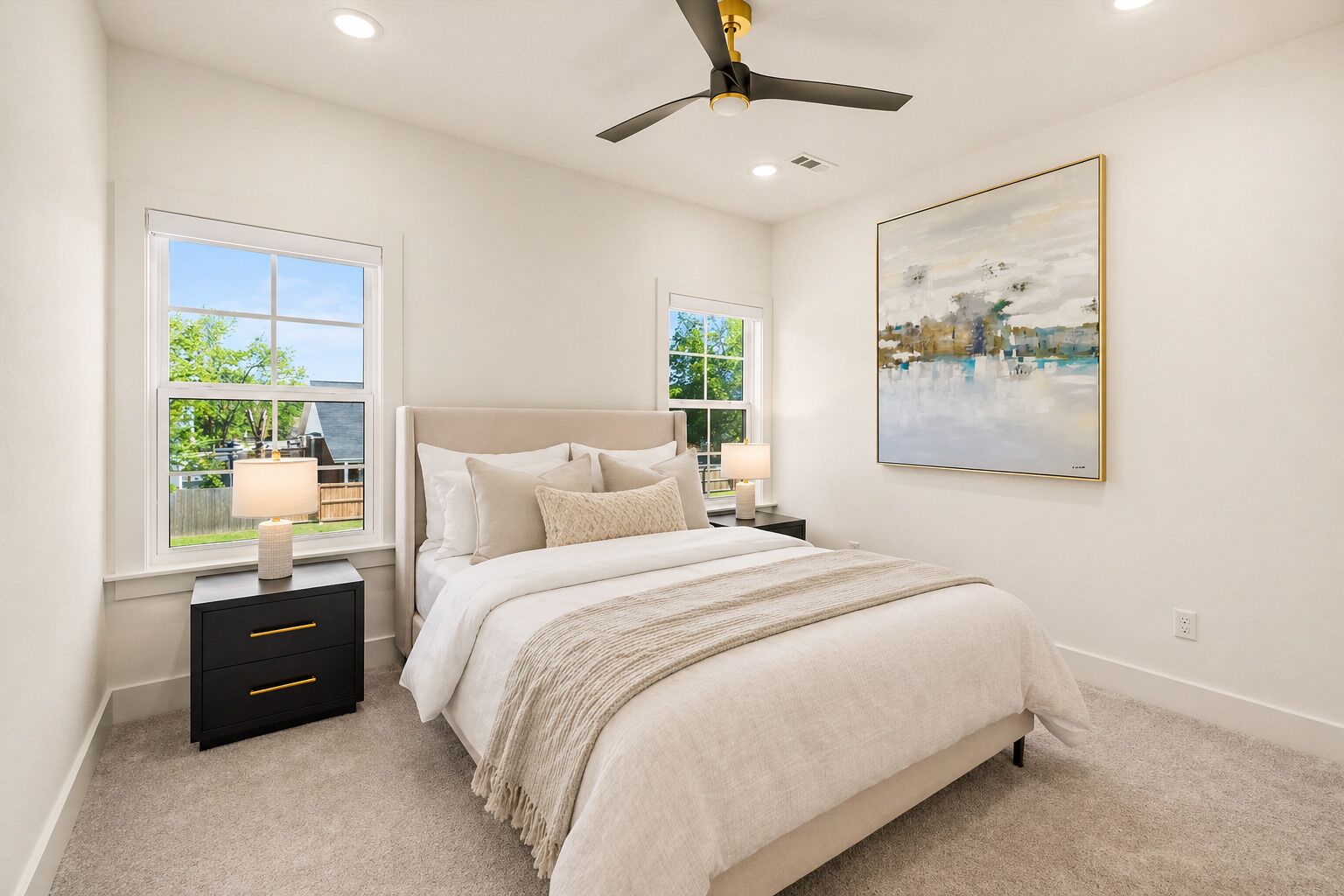 A bedroom with a bed, nightstands, a ceiling fan, and a painting on the wall.