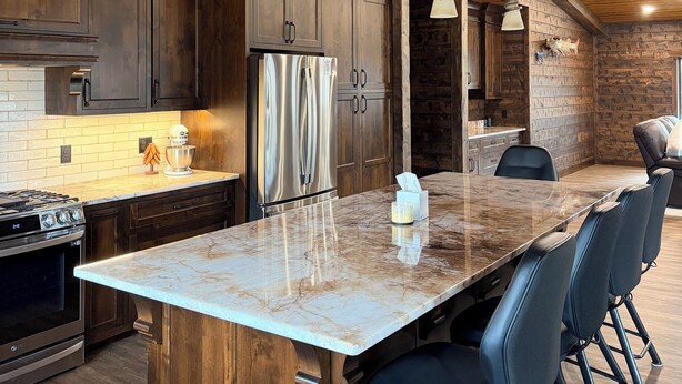 Una cocina moderna con armarios de madera, una isla de mármol y taburetes de bar.