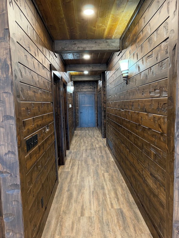 A narrow hallway with wooden walls and a blue door at the end.