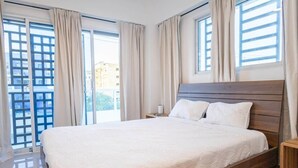 A bedroom with a bed, curtains, and a window with a view of buildings.