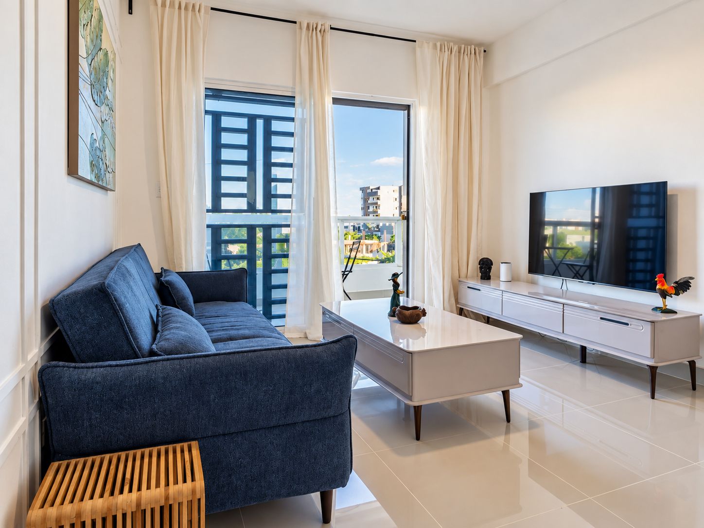 Un salon moderne avec un canapé, une table basse, un téléviseur et un balcon offrant une vue agréable.
