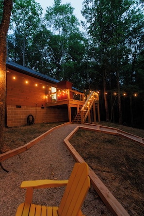 Eine Holzhütte mit Balkon, Treppe und Lichterketten.