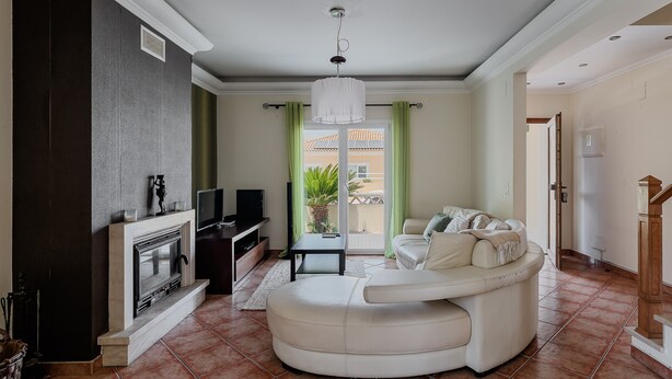 En stue med pejs, en hvid sofa, et fjernsyn og udsigt ud