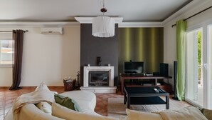 En stue med pejs, fjernsyn, sofa og spiseplads.