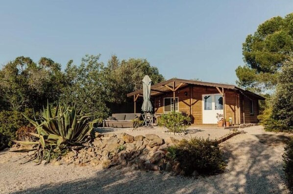 A wooden cabin with a porch, a dining table, and a chair. - Writer's retreat: cottage with outdoor bath and pool (Moncarapacho)