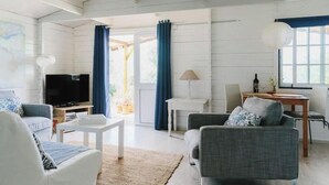 Uma sala de estar com televisão, sofá, mesa de centro e um espaço de jantar com mesa e cadeiras.