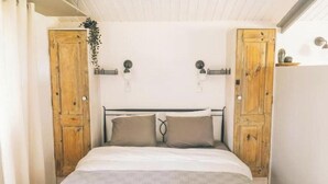 Une chambre à coucher avec un lit, deux portes en bois, un plafond blanc et une petite plante.