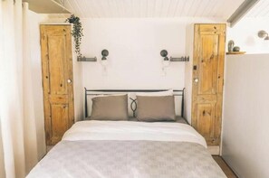 Ein Schlafzimmer mit einem Bett, zwei Holztüren, einer weißen Decke und einer kleinen Pflanze.