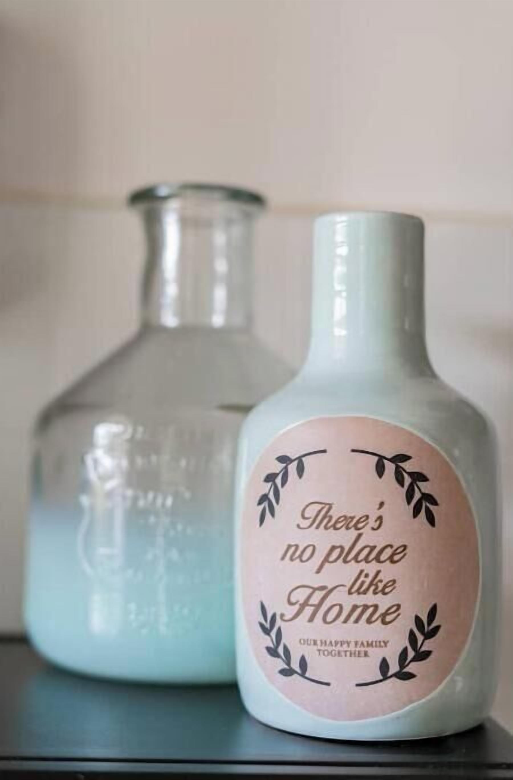 Two glass bottles with labels, one with a pink label and the other clear.
