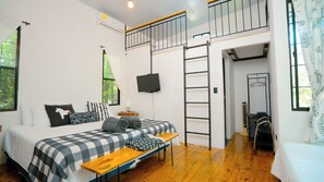 Une chambre avec un lit, un bureau, une télévision, une échelle et une fenêtre.