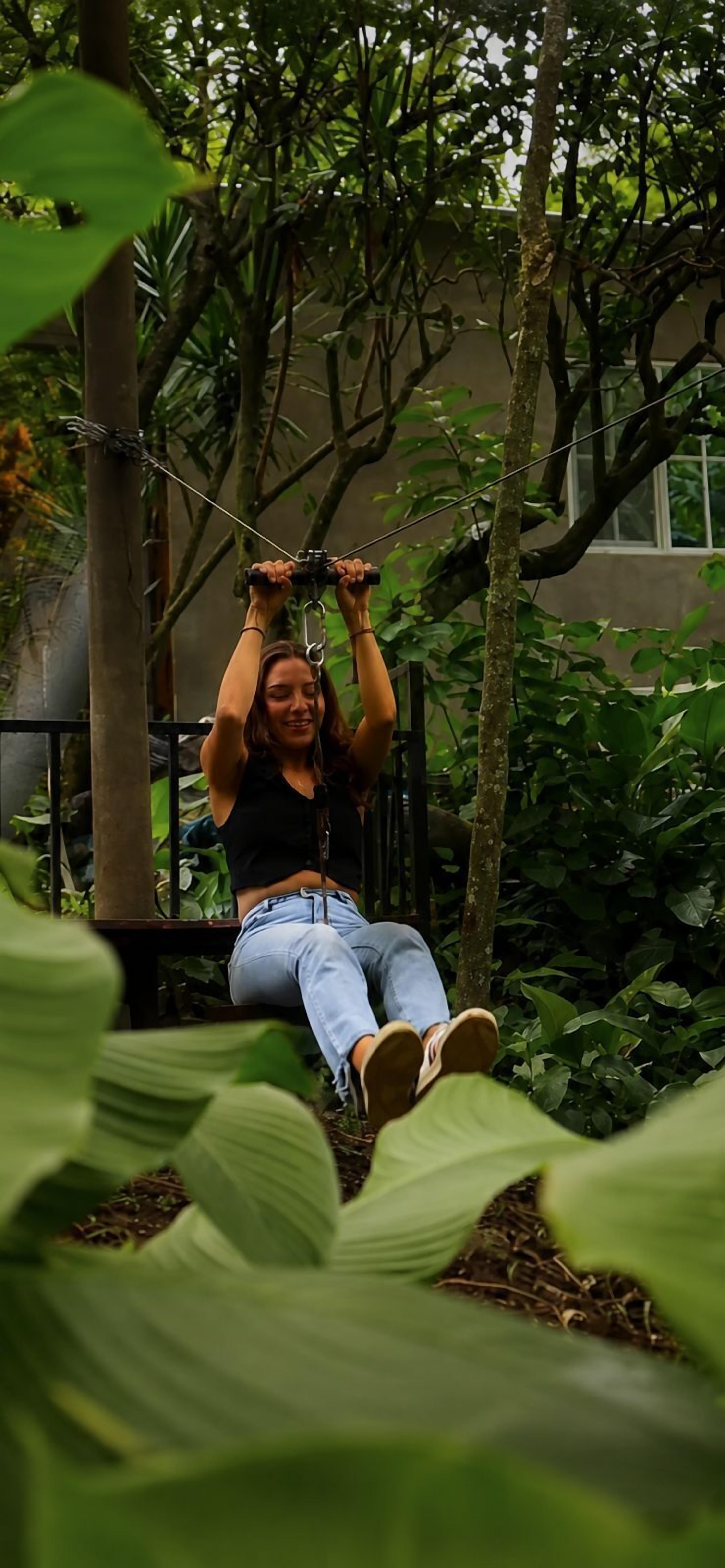 A person on a swing in a lush, green outdoor setting.