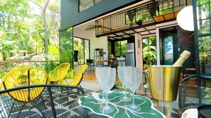 Un espace extérieur moderne, aménagé avec des chaises jaunes, une table verte et un seau à champagne.