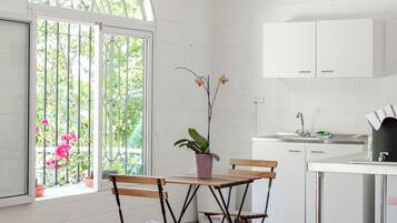 A kitchen with white cabinets, a wooden bench, and a window with a view of greenery.