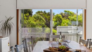 Zona de menjador amb una taula preparada per a dues persones, una ampolla de vi i una varietat de fruites i formatges.