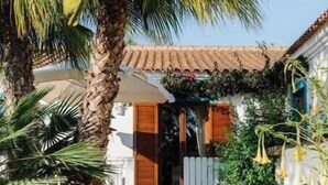 A house with a tiled roof, a front porch, and a large palm tree. - Oasis in tropical gardens with swimming pool (Moncarapacho)