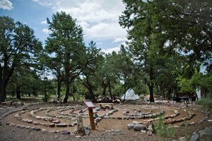A campsite with a circular walking path, a small wooden bench, and a tent in the background. - Golden Harmony Cottage (Crestone)