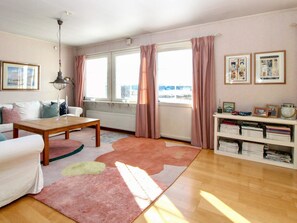 A living room with a sofa, a coffee table, a bookshelf, and a window with curtains. - 4 Star Holiday Home in Grebbestad (Grebbestad)