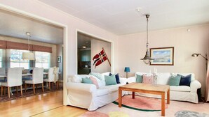 A living room with two white sofas, a wooden coffee table, and a flag on the wall. - 4 Star Holiday Home in Grebbestad (Grebbestad)