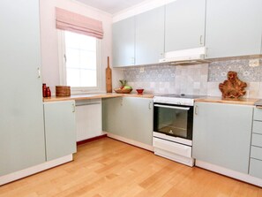 A kitchen with light blue cabinets, a white stove, and a wooden countertop. - 4 Star Holiday Home in Grebbestad (Grebbestad)