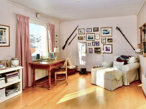 A cozy living room with a wooden desk, a white sofa, and a bookshelf filled with books. - 4 Star Holiday Home in Grebbestad (Grebbestad)