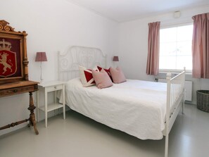A bedroom with a white bed, a wooden desk, a red and white framed picture, and a window with curtains. - 4 Star Holiday Home in Grebbestad (Grebbestad)