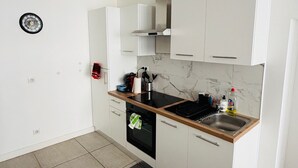 Moderni keittiö, jossa on valkoiset kaapit, musta liesi ja marmorista tehty välitila.