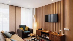 A modern living room with a sofa, a leather armchair, a wooden entertainment unit, and a flat-screen TV mounted on the wall. - Neuilly House Chic & Cosy | Ideally Located (Neuilly-Saint-Front)