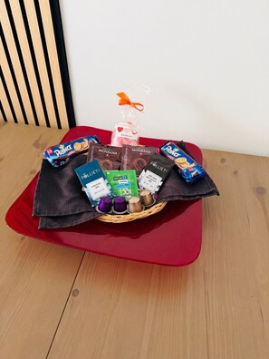A basket of chocolates and snacks on a red cushion.