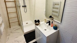 A bathroom with a shower, a sink, a mirror, and a towel rack. - Neuilly House Chic & Cosy | Ideally Located (Neuilly-Saint-Front)