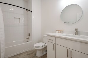 Un baño moderno con bañera, inodoro, lavabo y espejo.