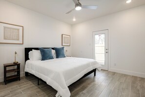 Un dormitorio con cama, mesita de noche, ventilador de techo y cuadros en las paredes.