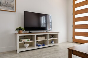 Ein Flachbildfernseher auf einer weißen Unterhaltungseinrichtung mit Regalen, einer Pflanze und dekorativen Gegenständen.