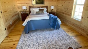 A bedroom with a bed, two bedside tables, a ceiling fan, a window, and a painting on the wall.