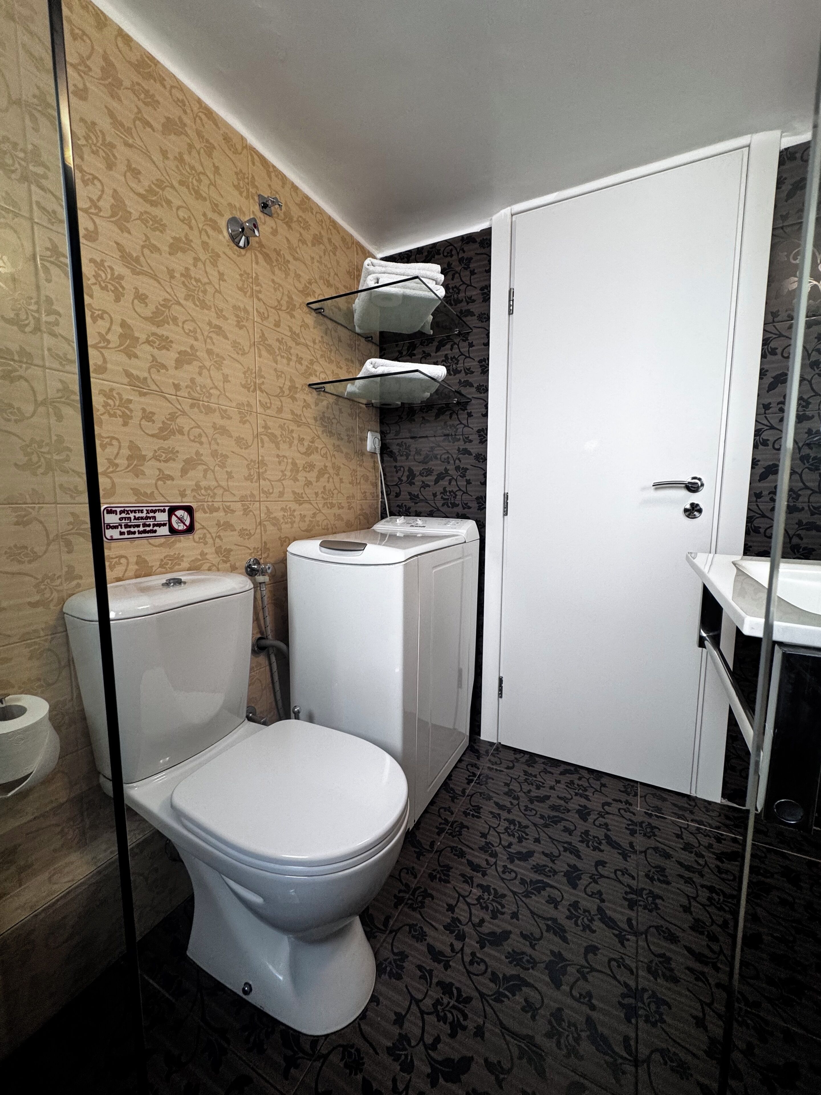 A bathroom with a toilet, a washing machine, and a sink.