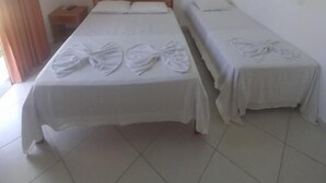 Une chambre d’hôtel avec deux lits, une tête de lit en bois, une table de chevet et un sol carrelé.