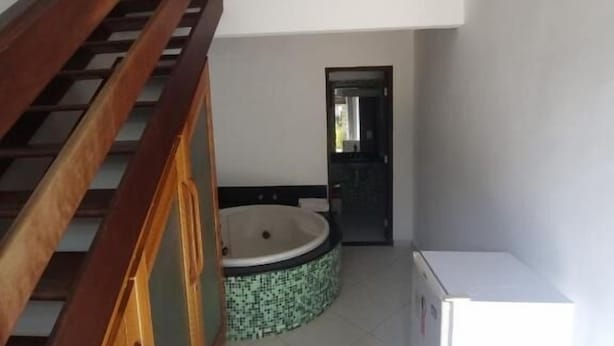 Une petite pièce, de taille modeste, avec un escalier en bois, un évier et un réfrigérateur blanc.